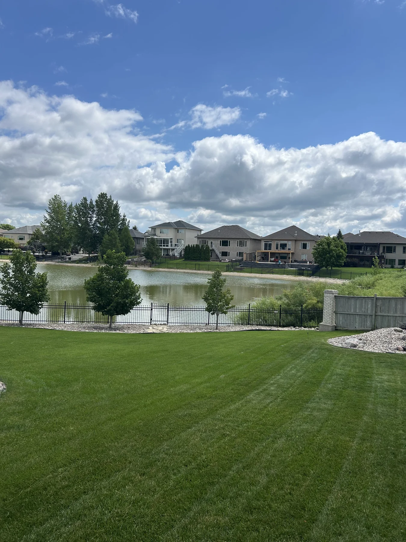 Freshly maintained striped residential lawn beside a pond