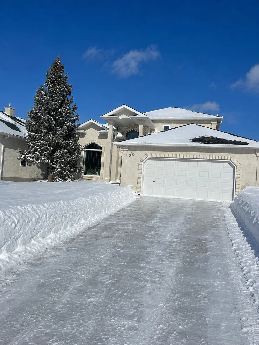 Wide residential driveway cleared of snow under a blue winter sky